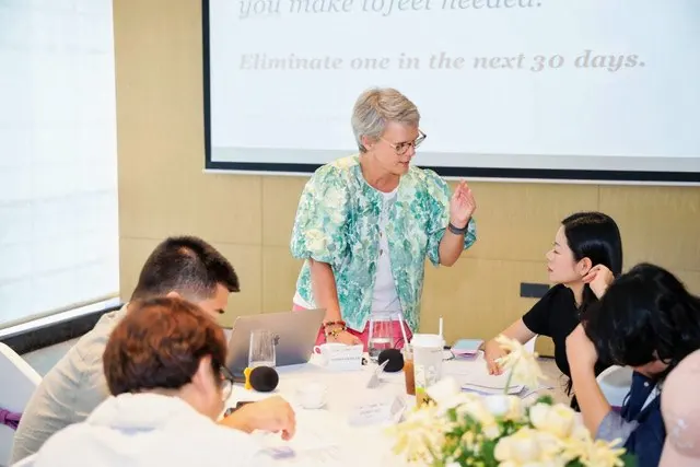 Ivanka Menken standing at a table of founders, talking a decision through with them